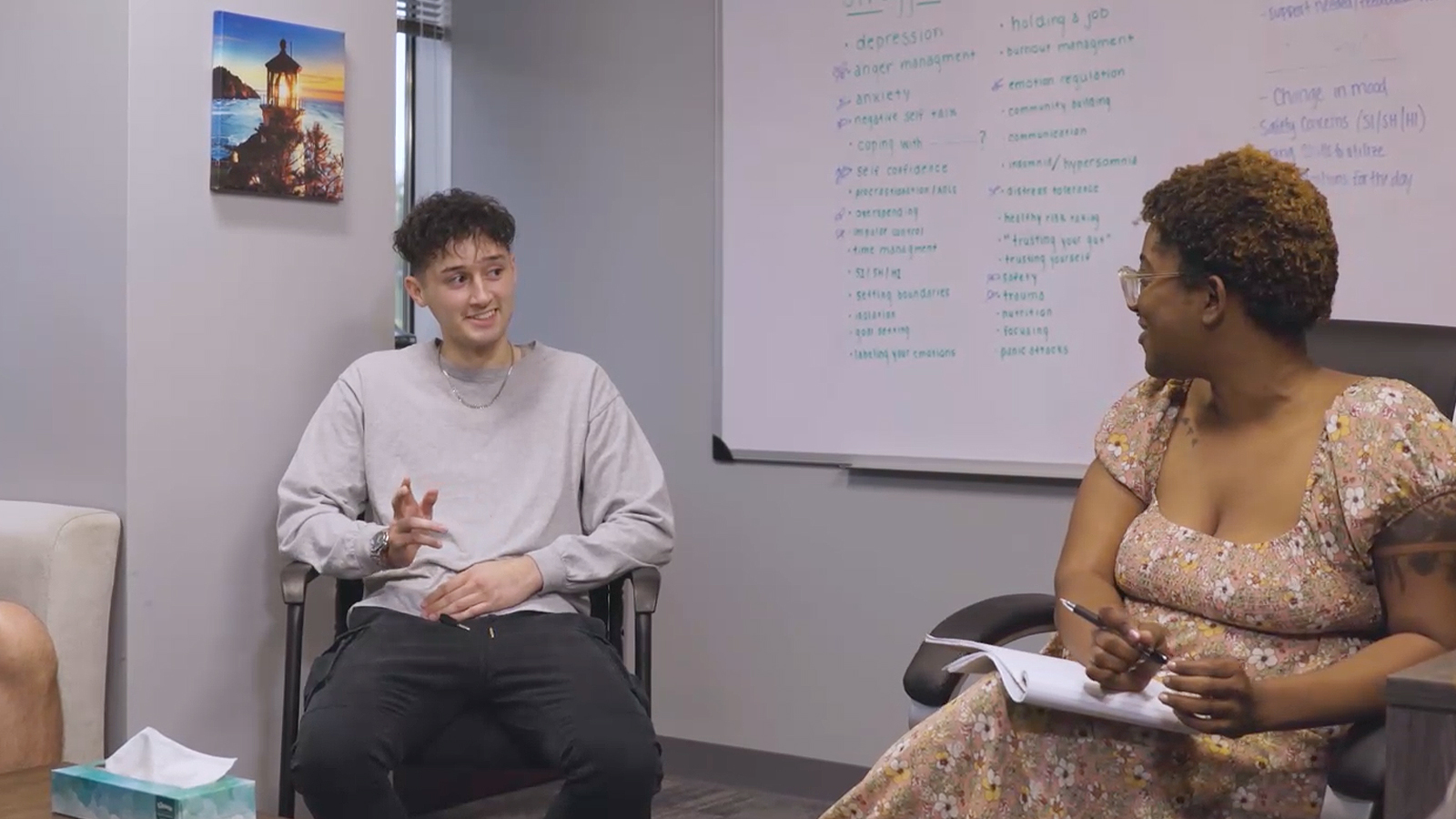 People in a therapy session with whiteboard backdrop.