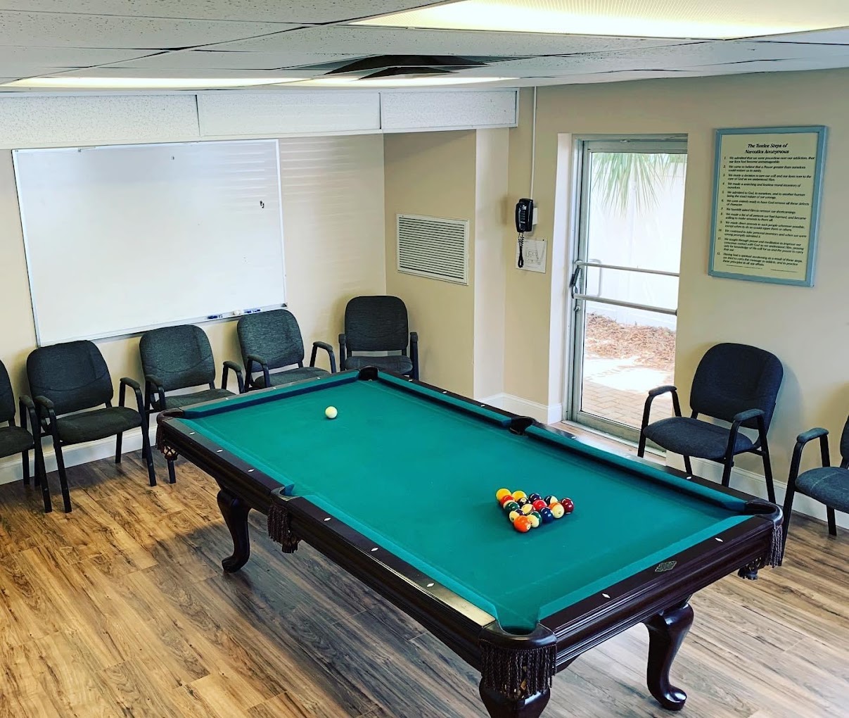 Recreational room with a pool table and chairs along the wall.