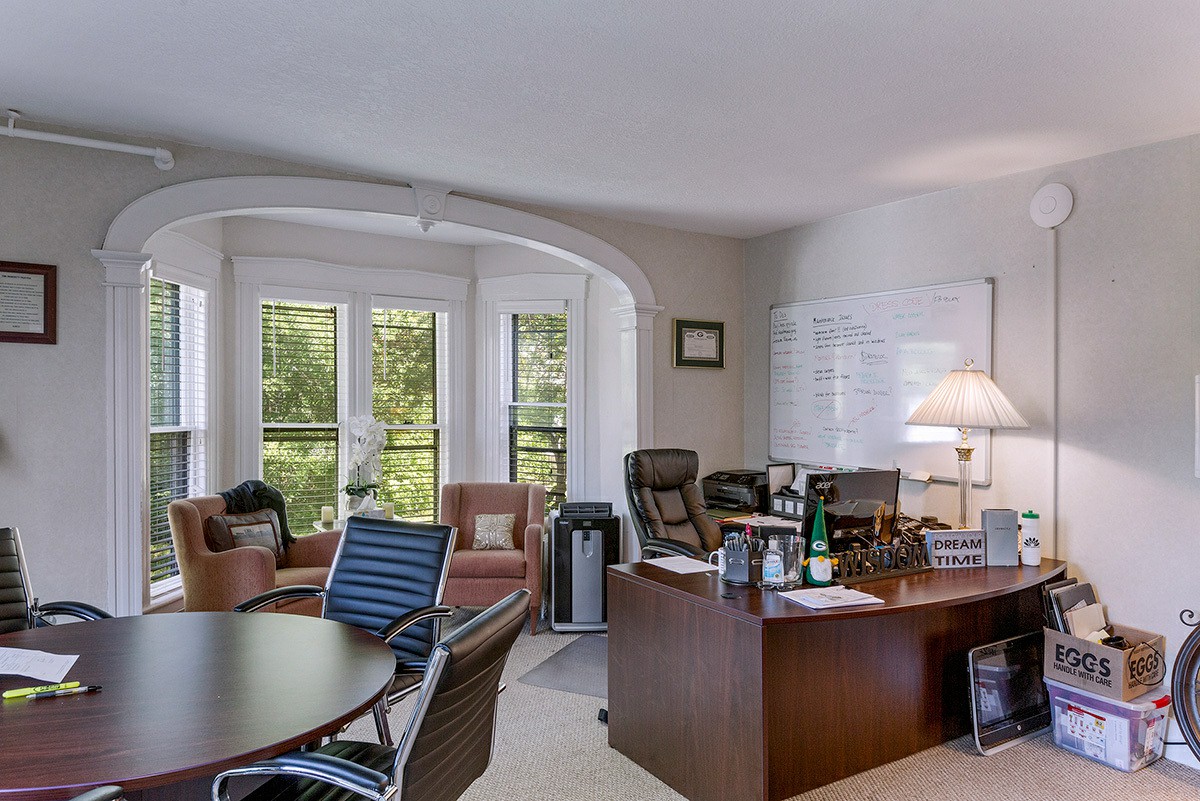 Office with wood desk, black chairs, and a whiteboard
