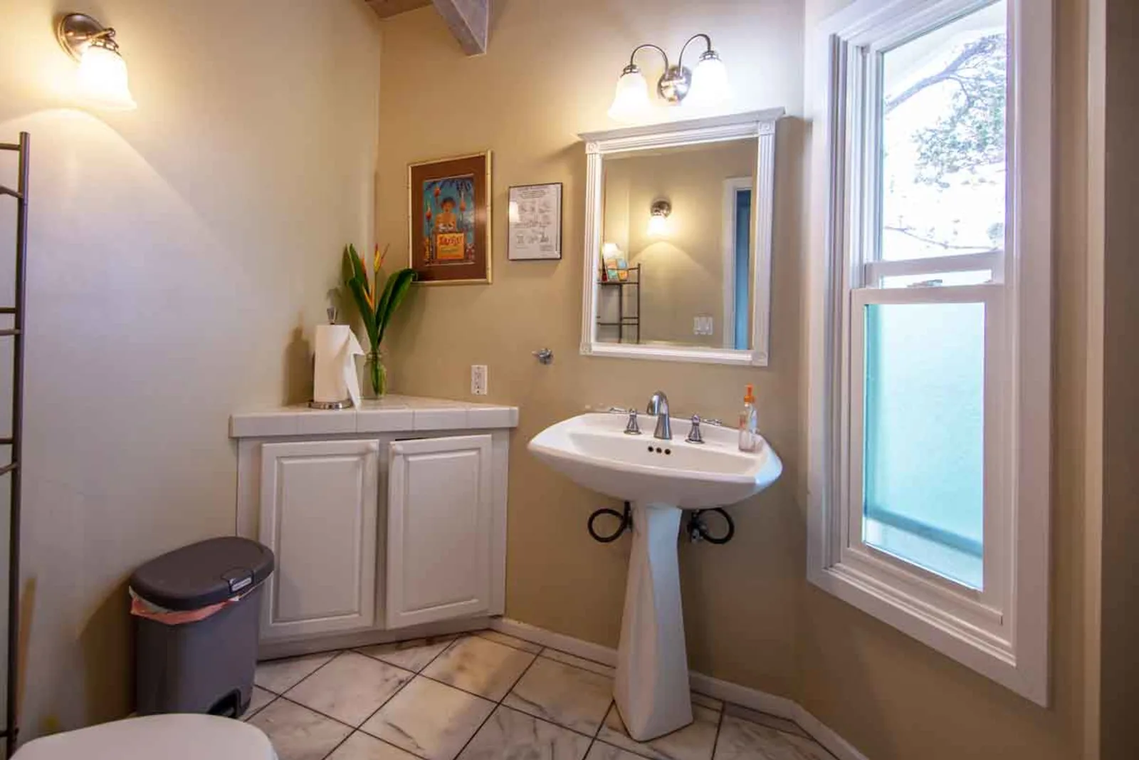 Pedestal sink and mirror in softly lit bathroom