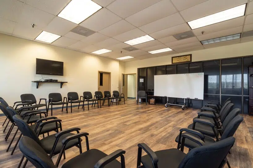 Group therapy room arranged with chairs in a circle, a whiteboard, and a TV.