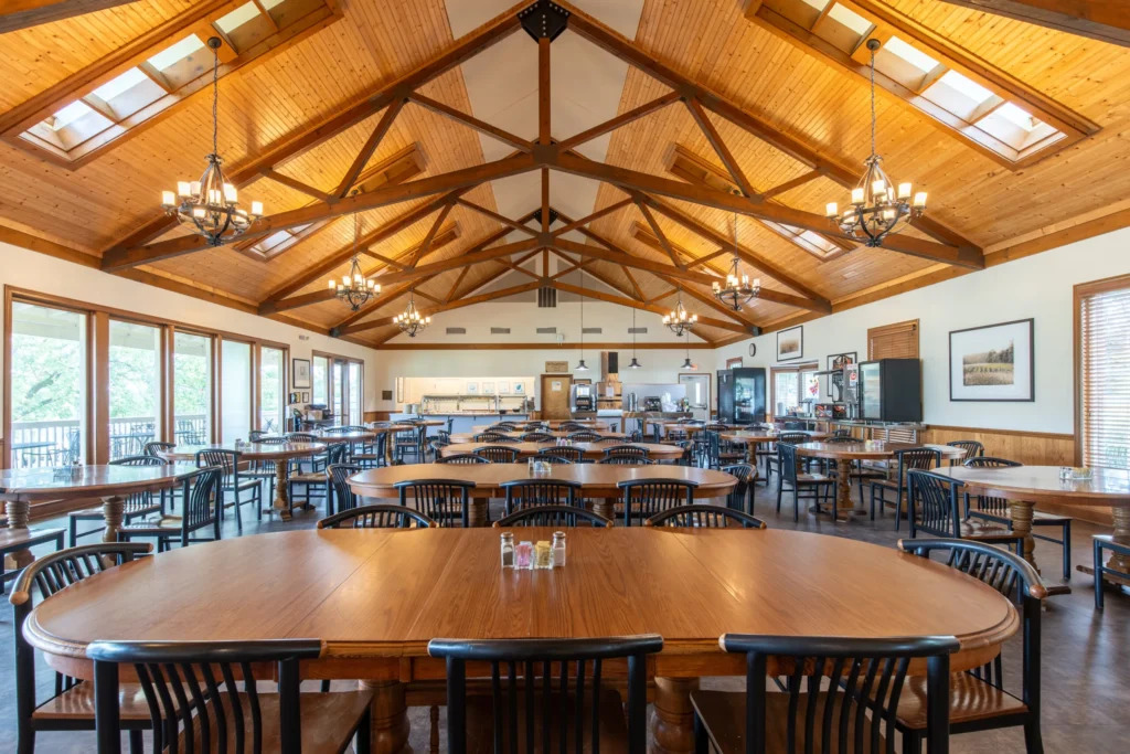 Wood-ceiling dining hall with round tables and large windows