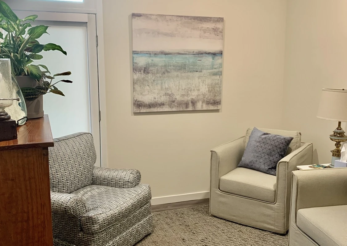Two armchairs with pillow and lamp beside potted plants
