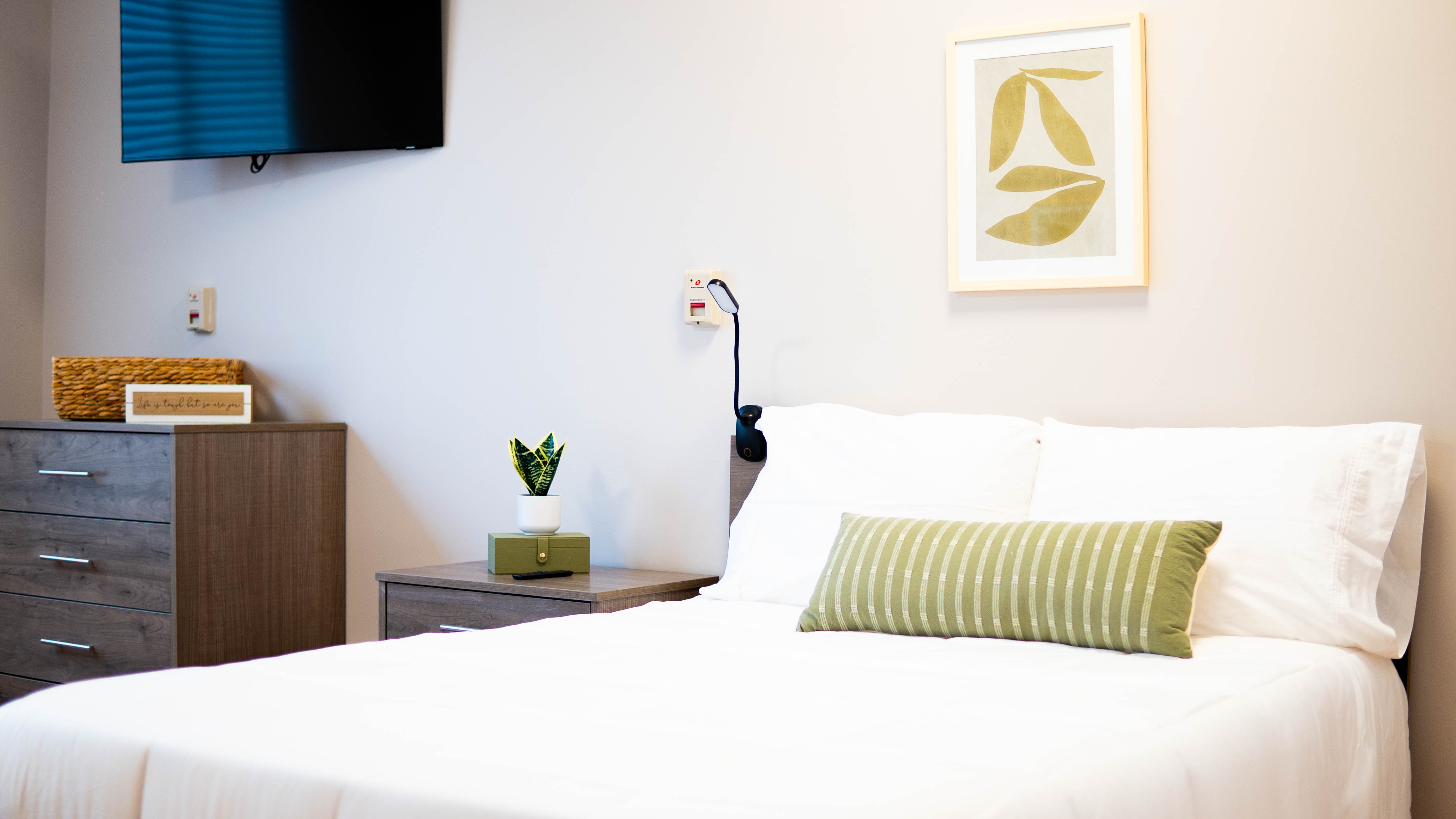 Modern rehab bedroom with a TV, nightstand, and decor.