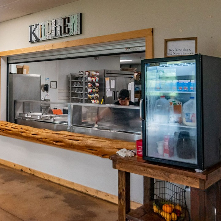 Open kitchen counter with staff and fridge nearby