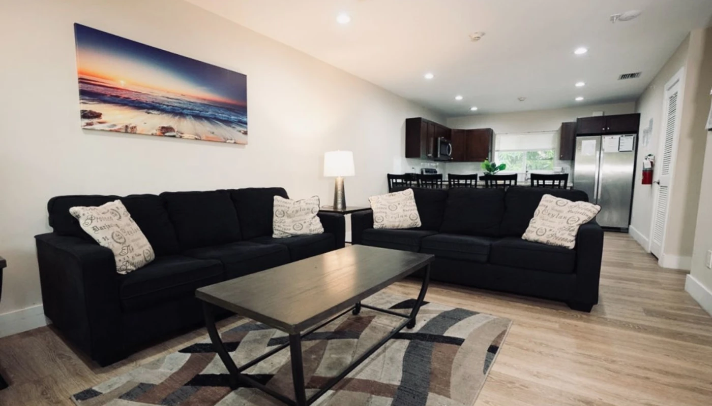 Stylish living area with black couches and a large beach painting.