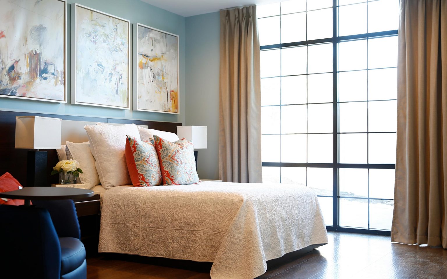 Stylish bedroom with a large window and abstract paintings.