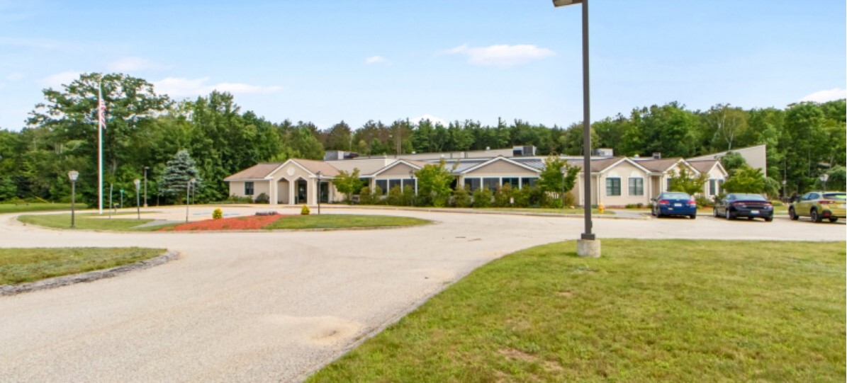 Exterior with a circular driveway, parking and trees.