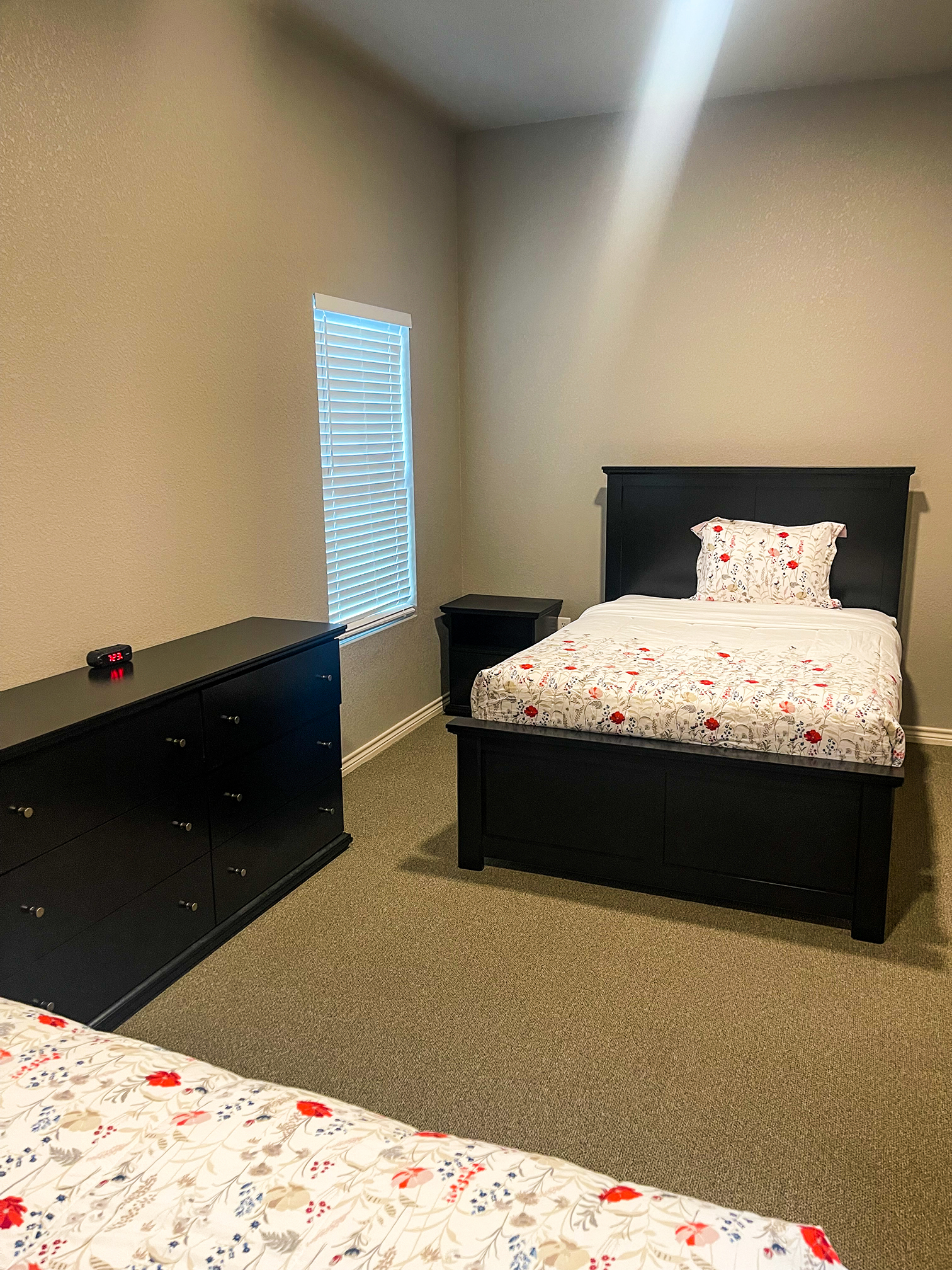 Private bedroom with a bed, dresser and a window.