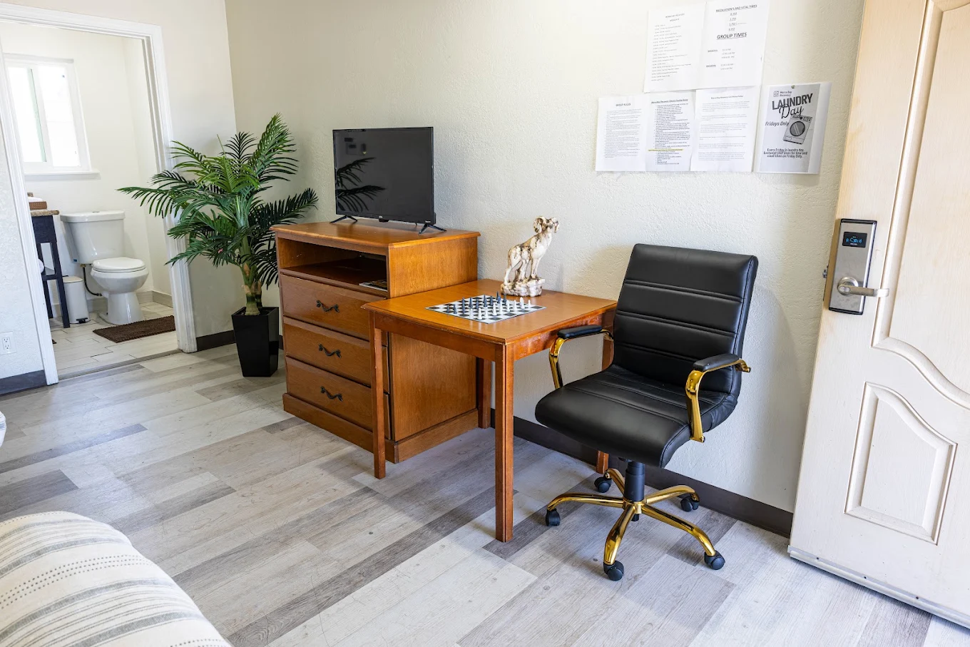 Small office area with wooden desk, black chair, and television