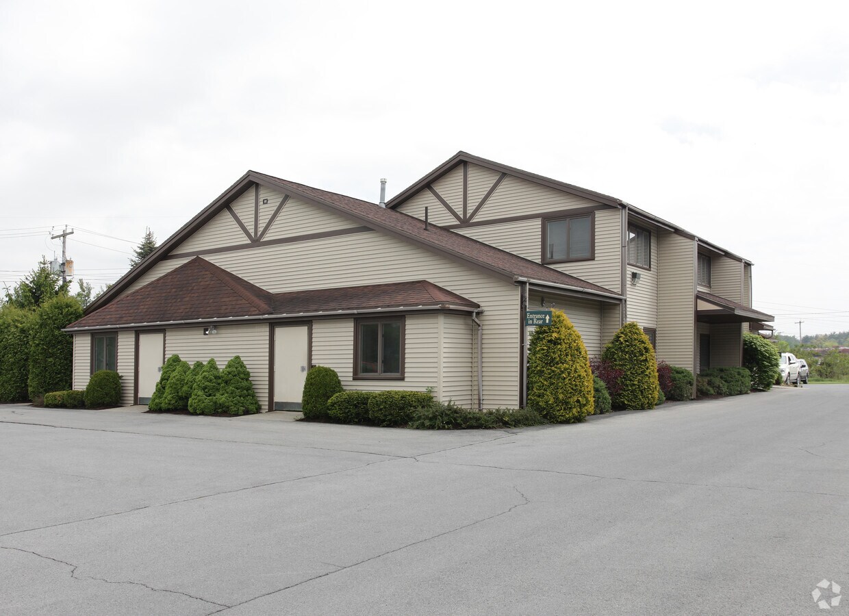 Beige two-story rehab building with brown roof and surrounding shrubs
