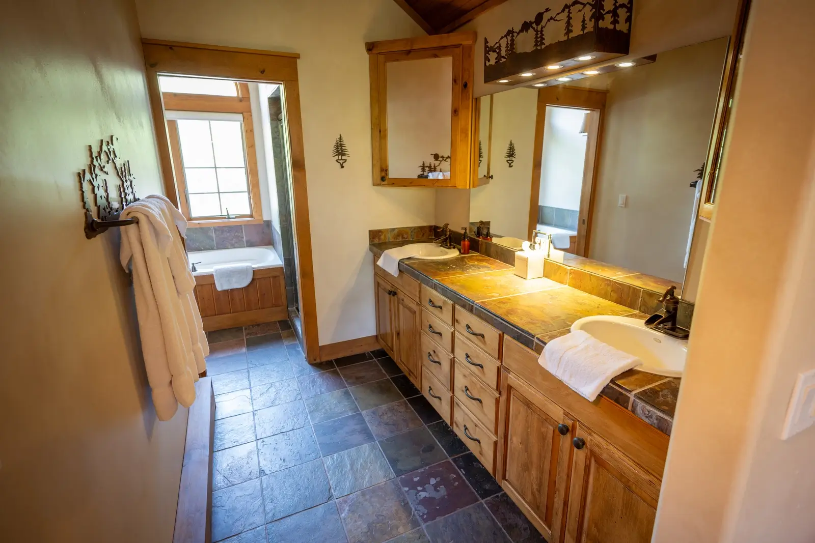 Double vanity bathroom with stone tile floors and a soaking tub