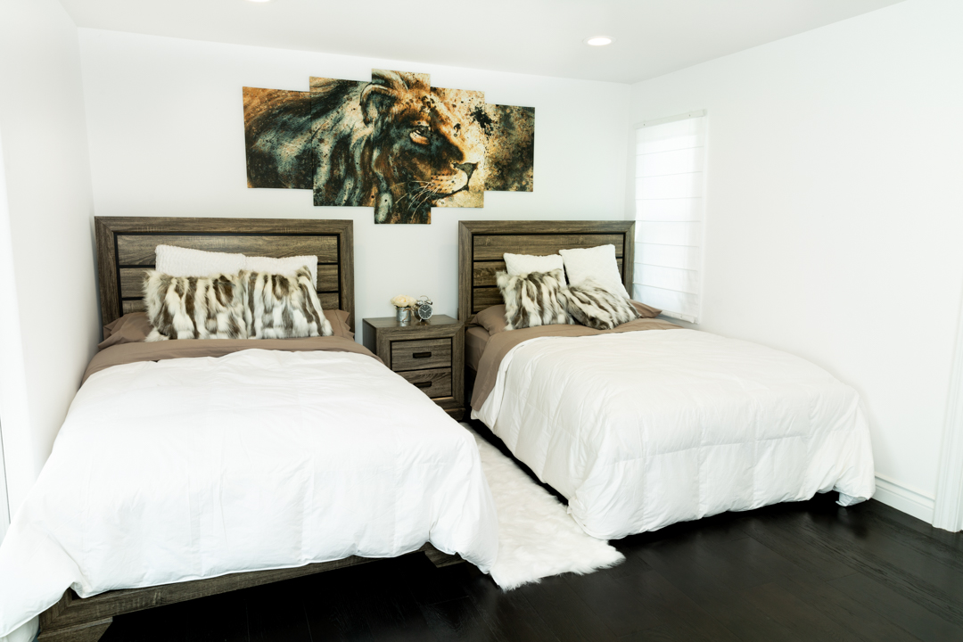 Two beds with fur pillows and lion artwork in a shared bedroom