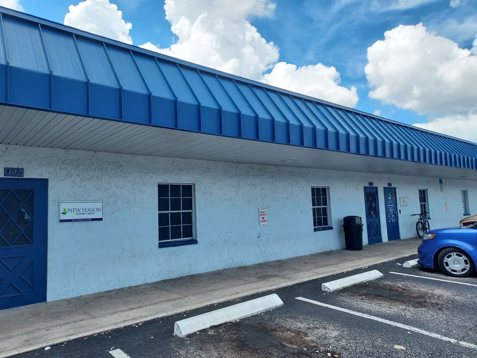 Blue-roofed building with New Season signage and parking