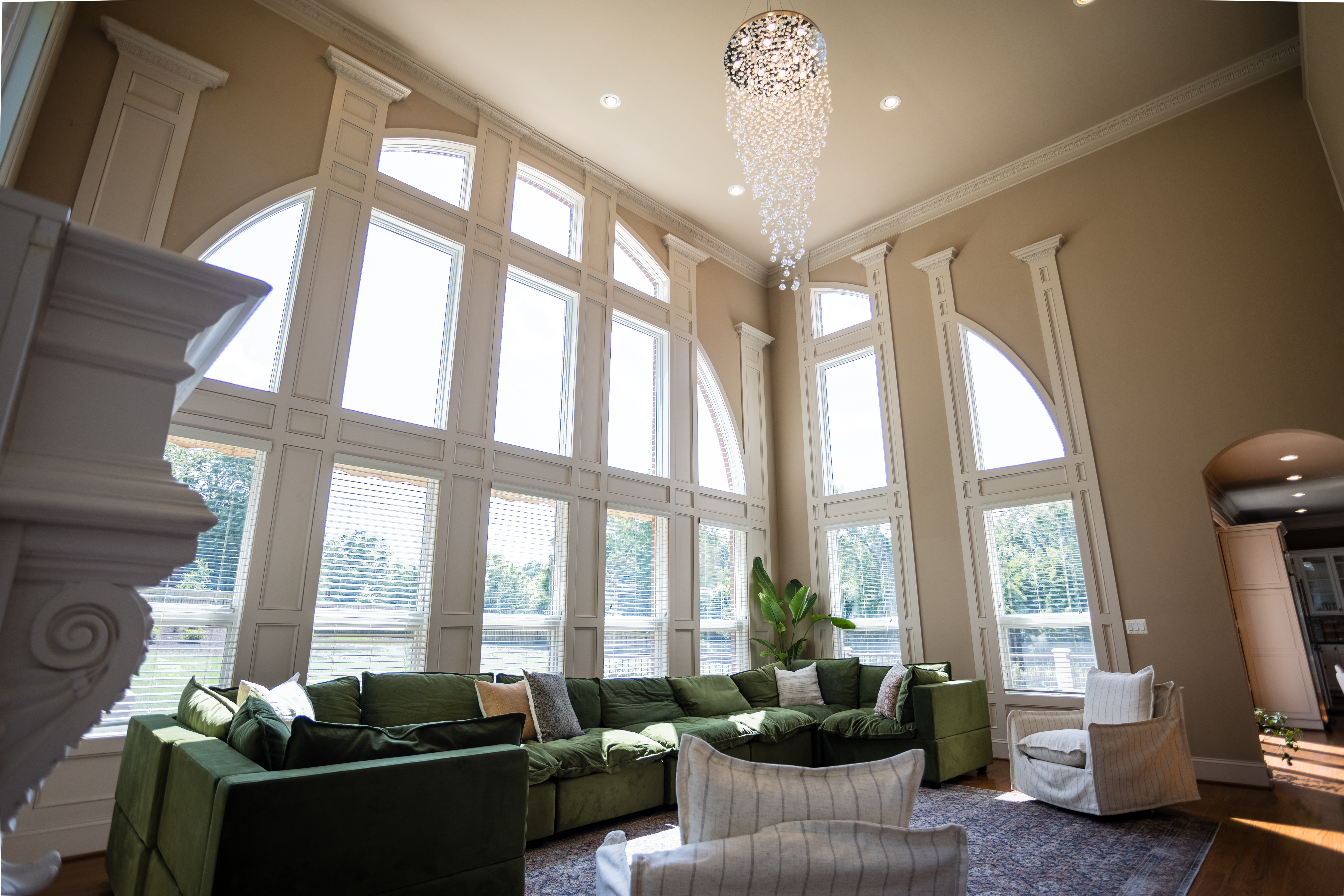 Green sectional couch in bright room with tall windows