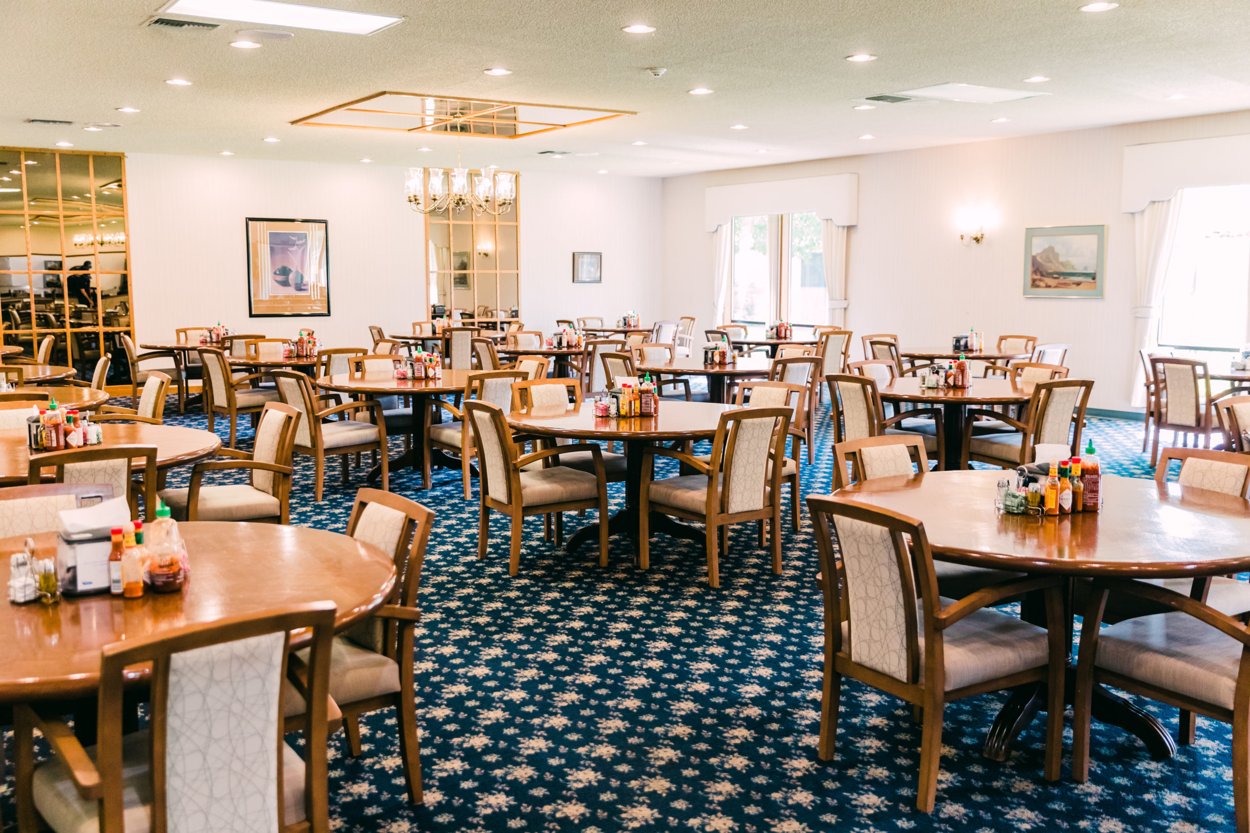 Spacious dining hall with round tables and condiments