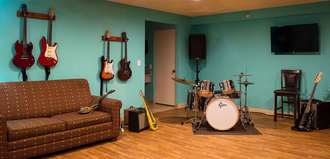 Music therapy room with guitars, a drum set, and seating.