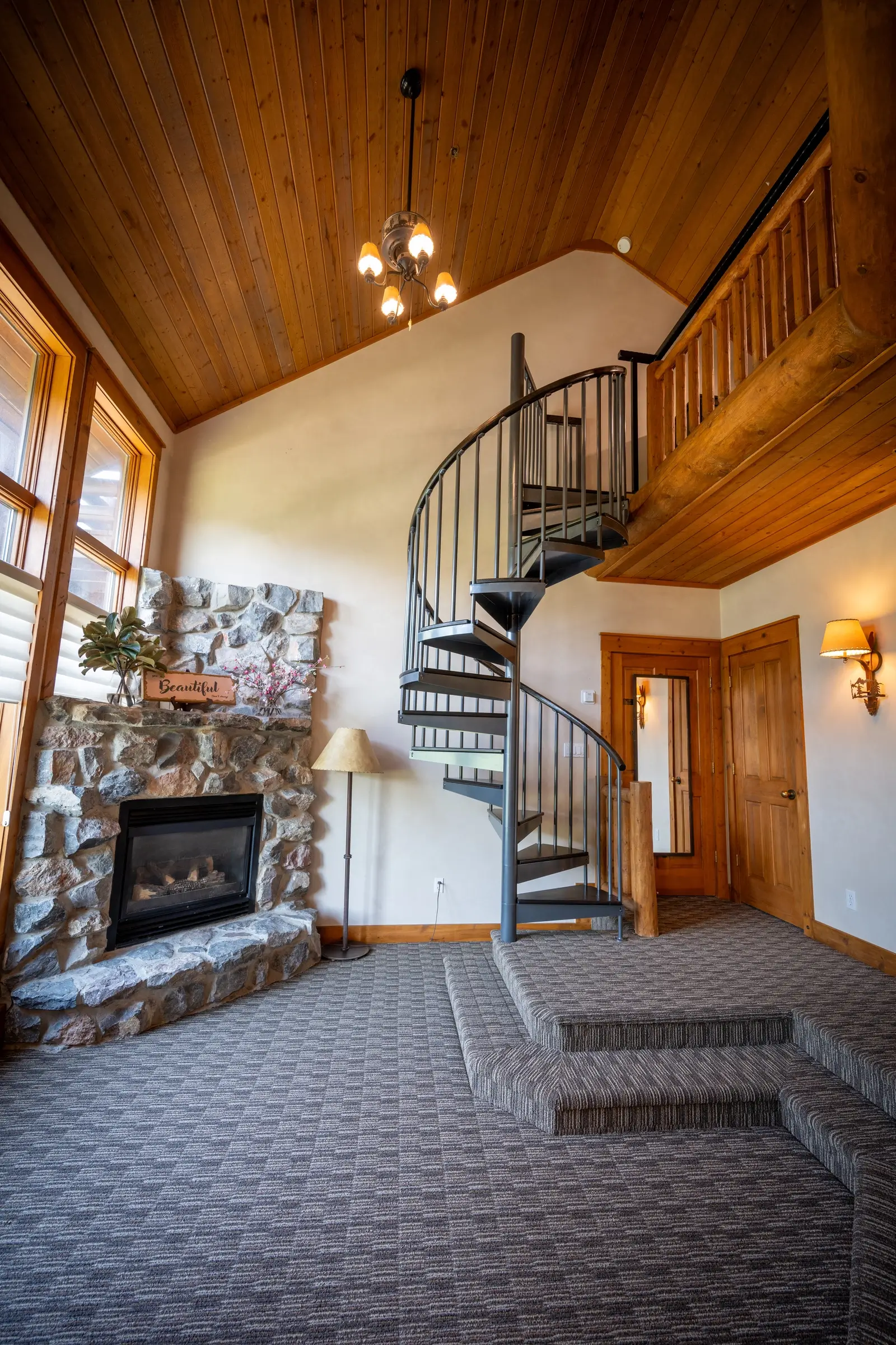 Stone fireplace with spiral staircase and cozy carpet