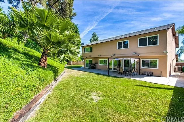 Two-story tan building with covered patio and green lawn