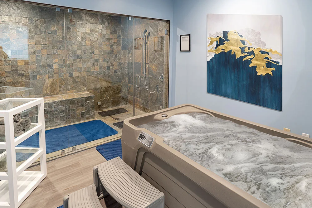 Wellness room featuring a hot tub and glass-enclosed stone-tiled shower