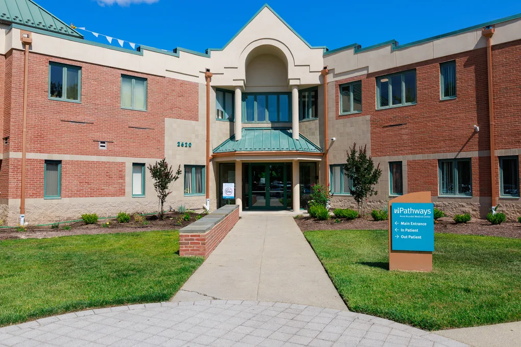 Brick rehab facility entrance with sign and landscaped walkway