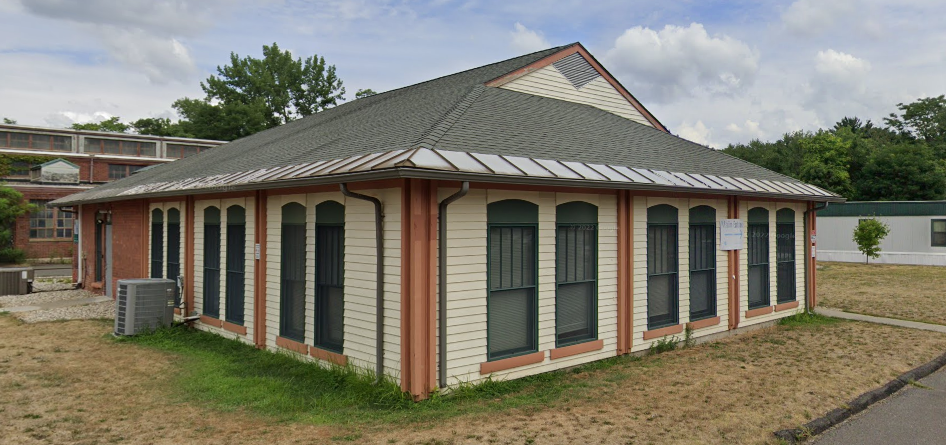 Side angle of beige recovery facility with green roof and windows