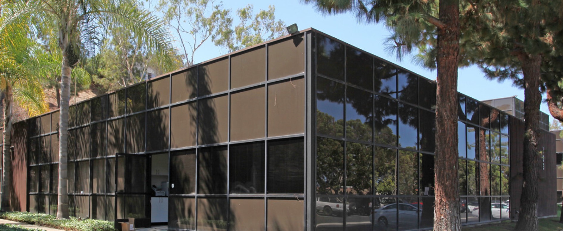 Modern, sleek building of Shoreline Recovery Center in Encinitas, surrounded by palm trees and ample parking.