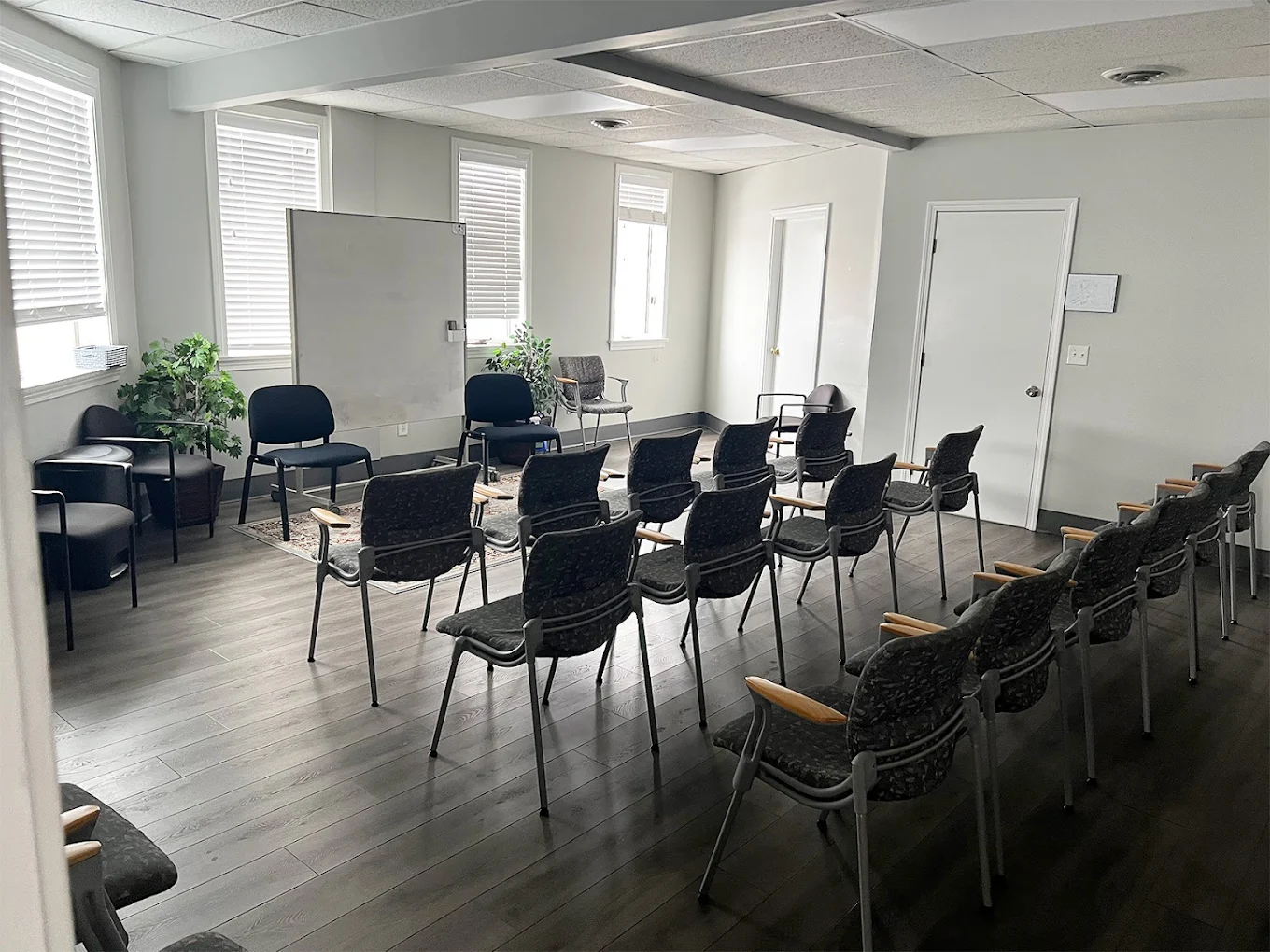 Conference-style room with rows of chairs, whiteboard, and natural light
