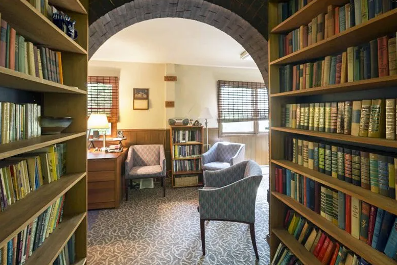 Cozy reading area with bookshelves, armchairs, and desk