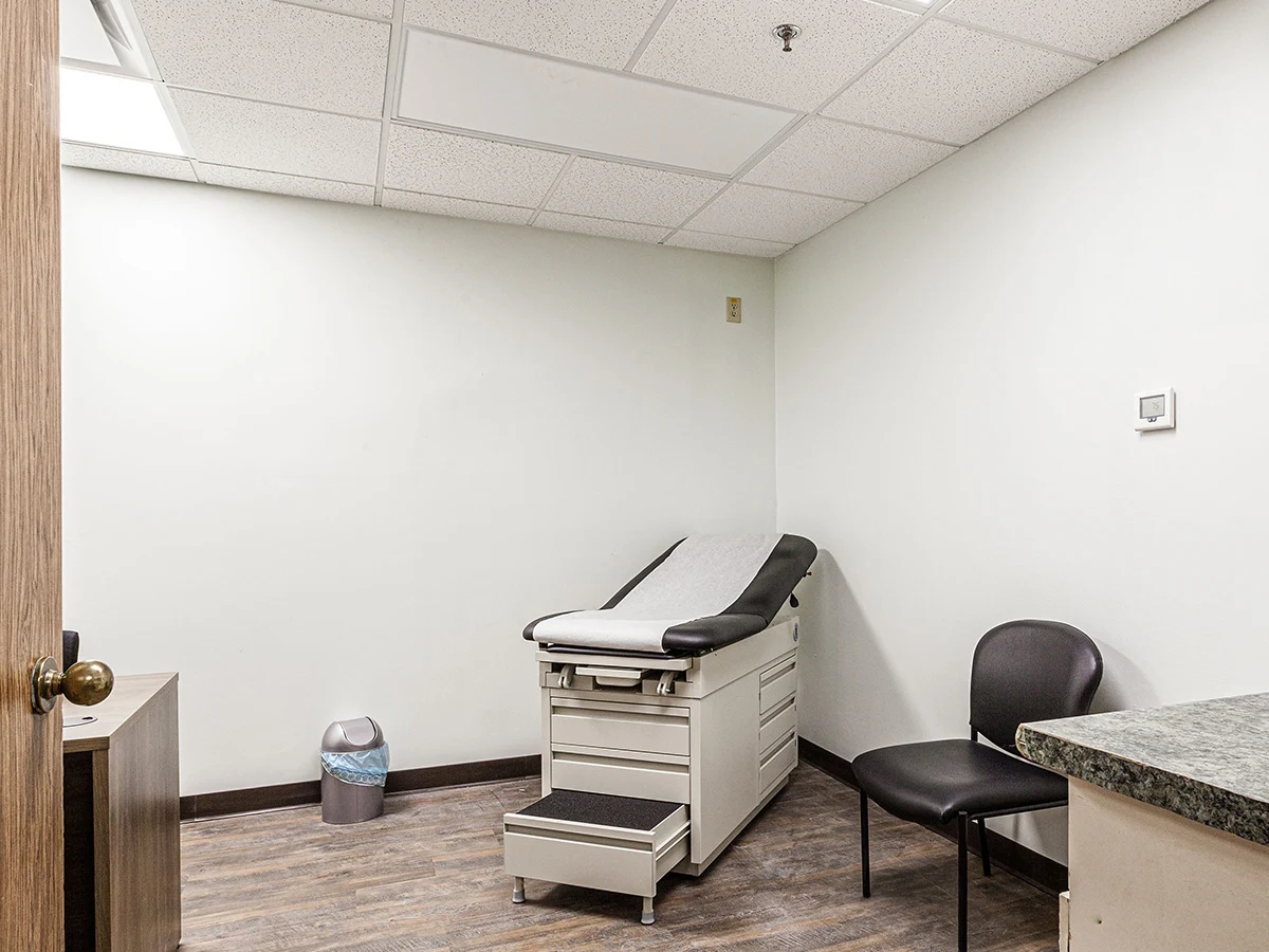 Medical exam room with bed, chair, and counter
