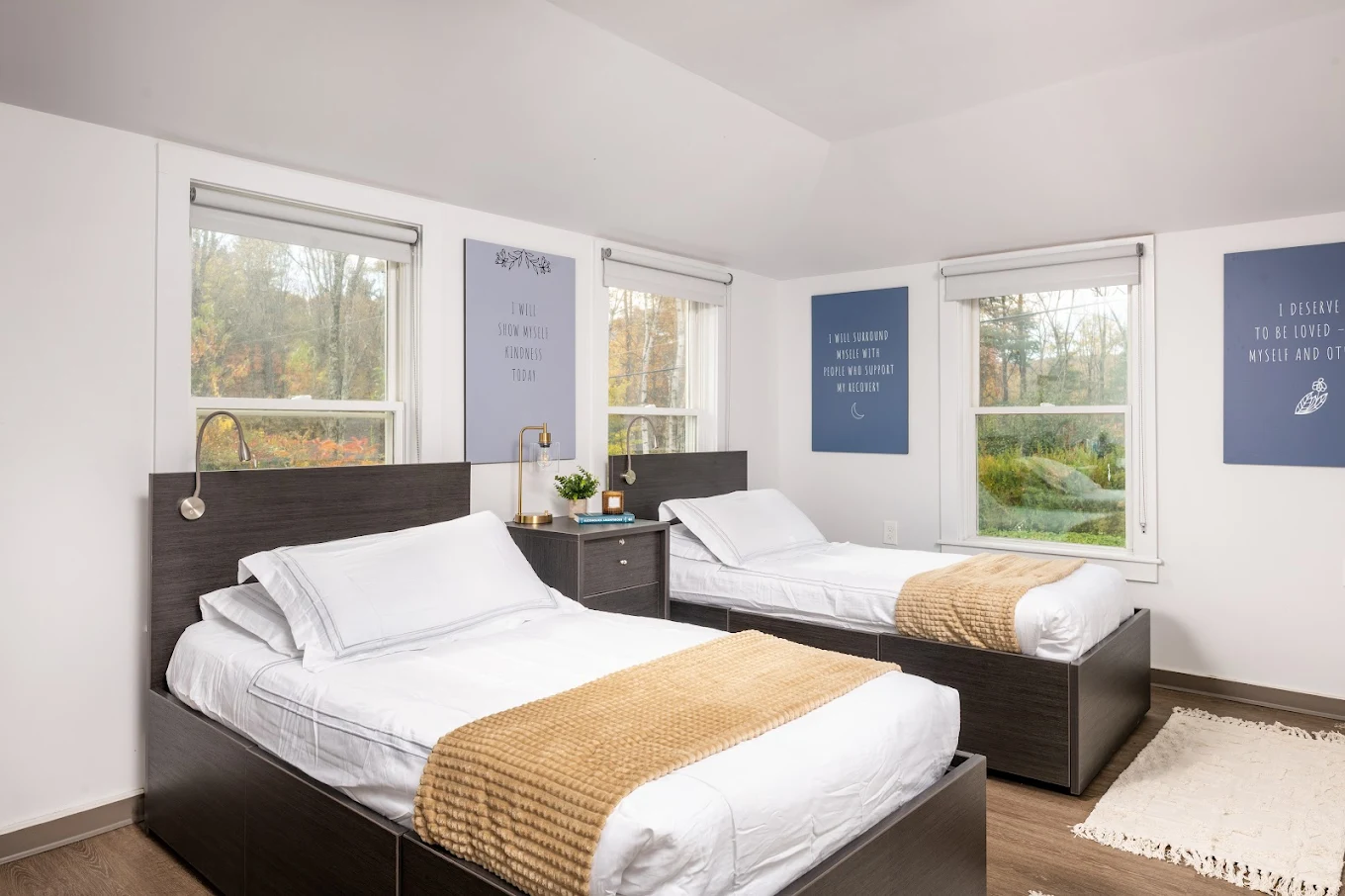 Twin beds with wood frames and wall quotes above