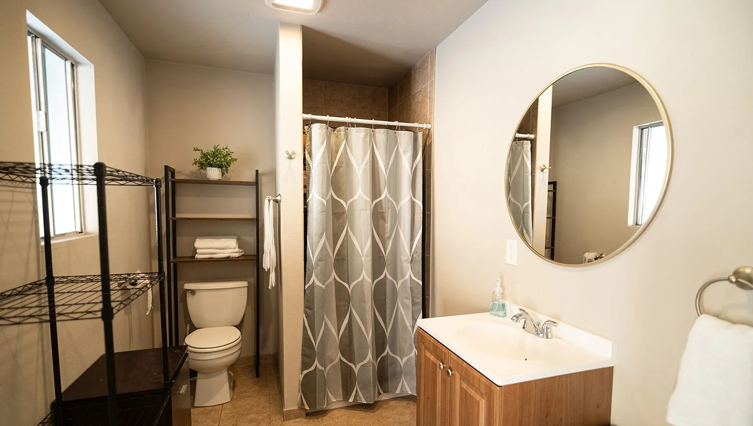 Clean bathroom with shower, shelving, and vanity sink.