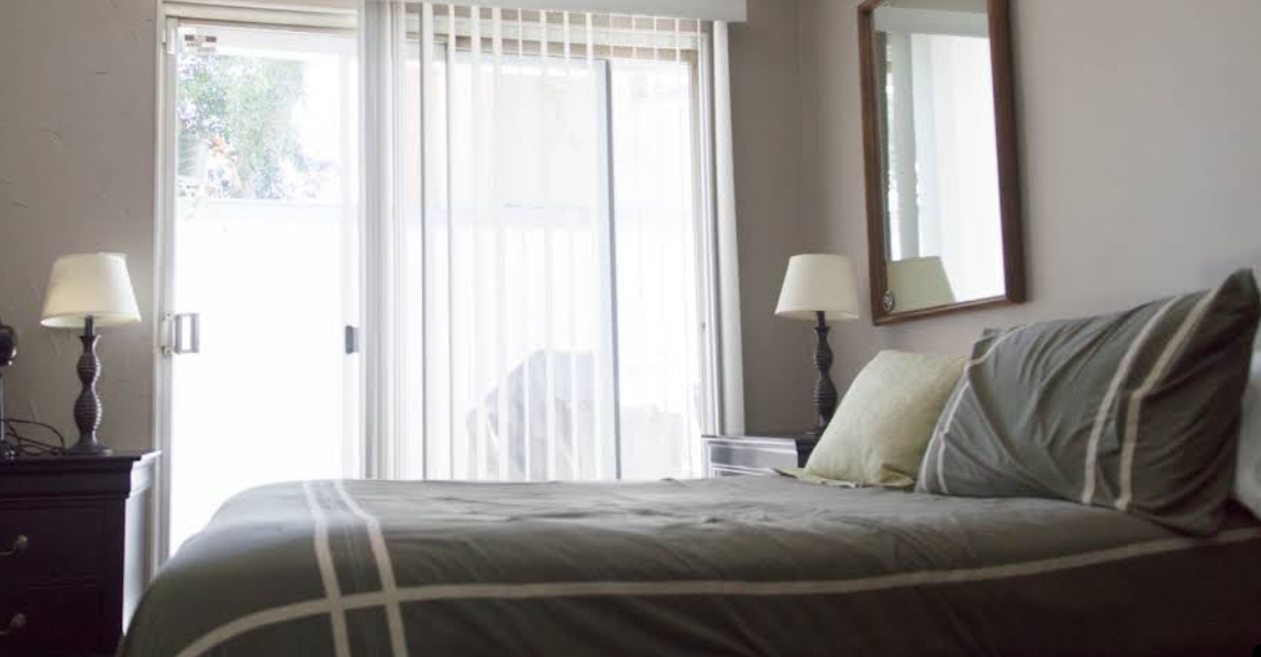 Bedroom with gray bedding, nightstands, and sliding glass door