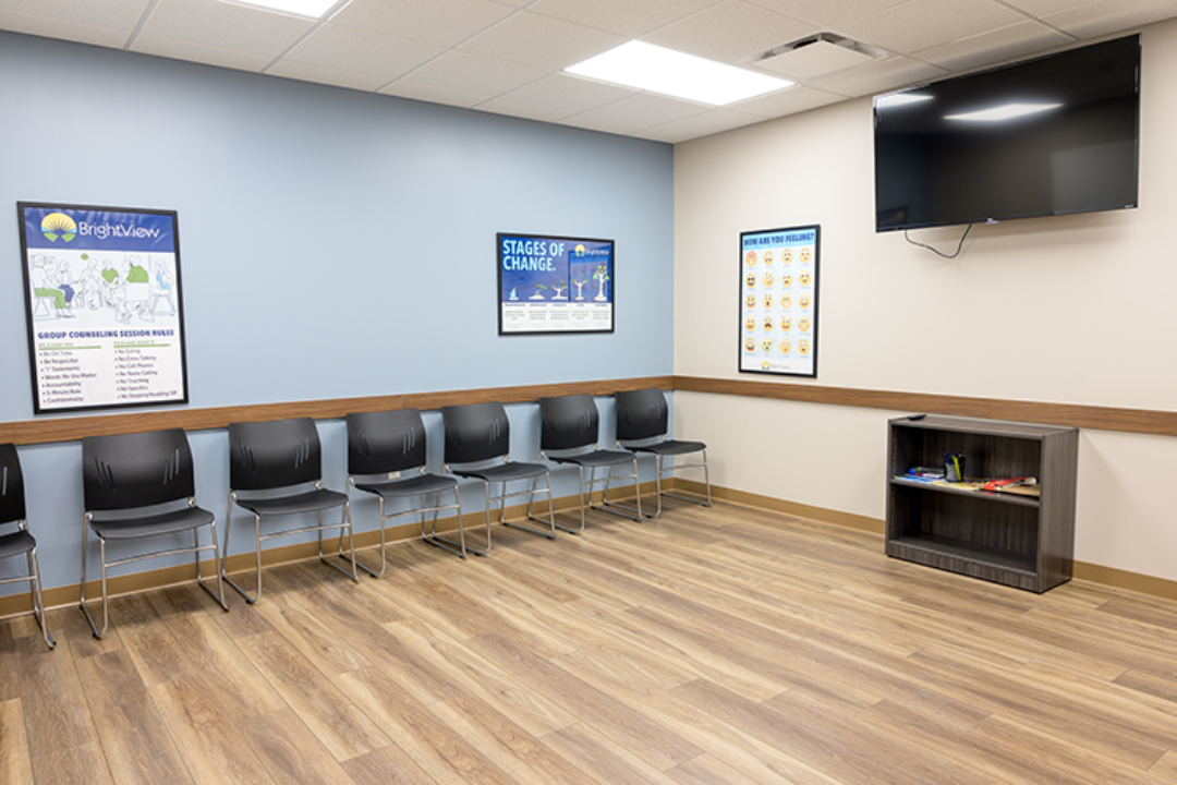 Group counseling room with row of chairs, television, recovery posters, and open floor space