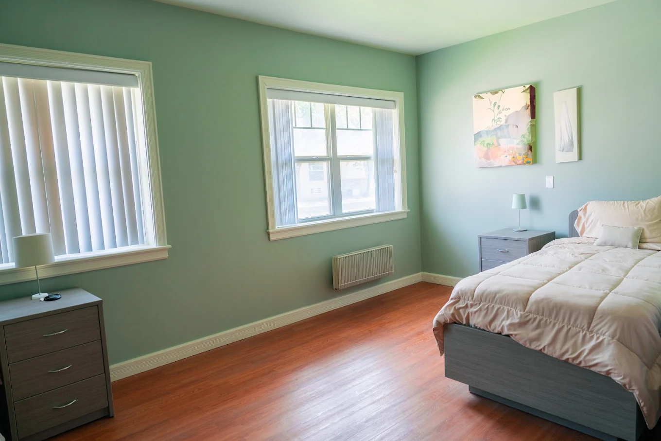 Simple bedroom with bed, dresser, and windows.