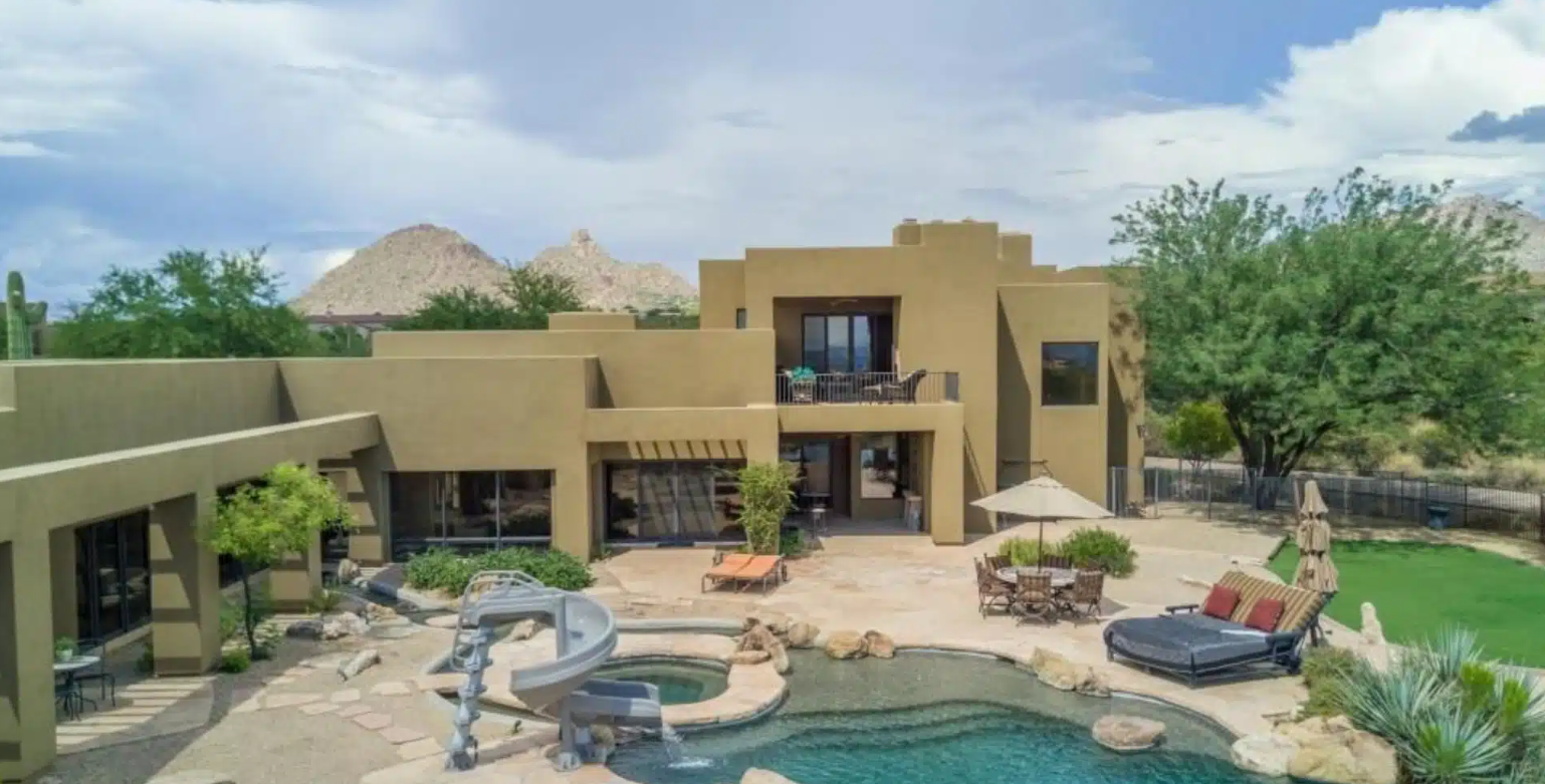 Outdoor pool with slide and lounge chairs in desert setting