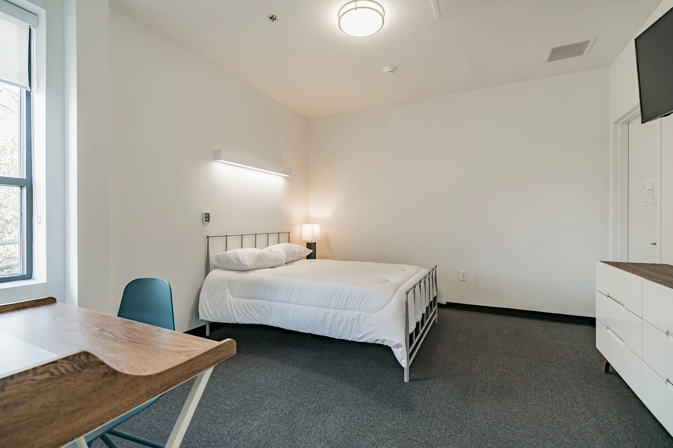 Private bedroom with bed, desk, and natural light
