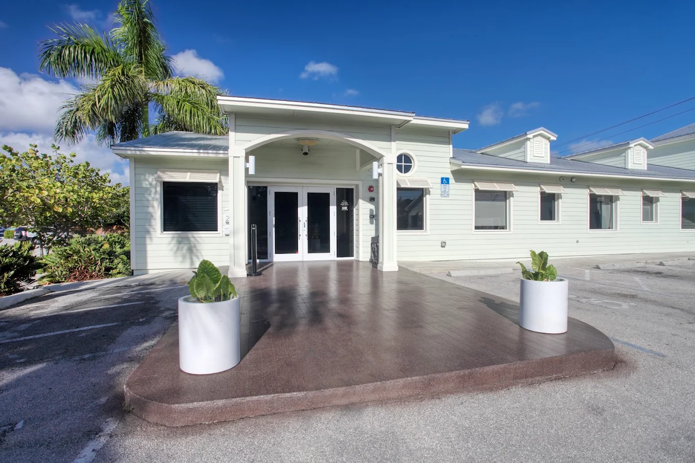 Facility entrance with white pillars, plants, and double doors