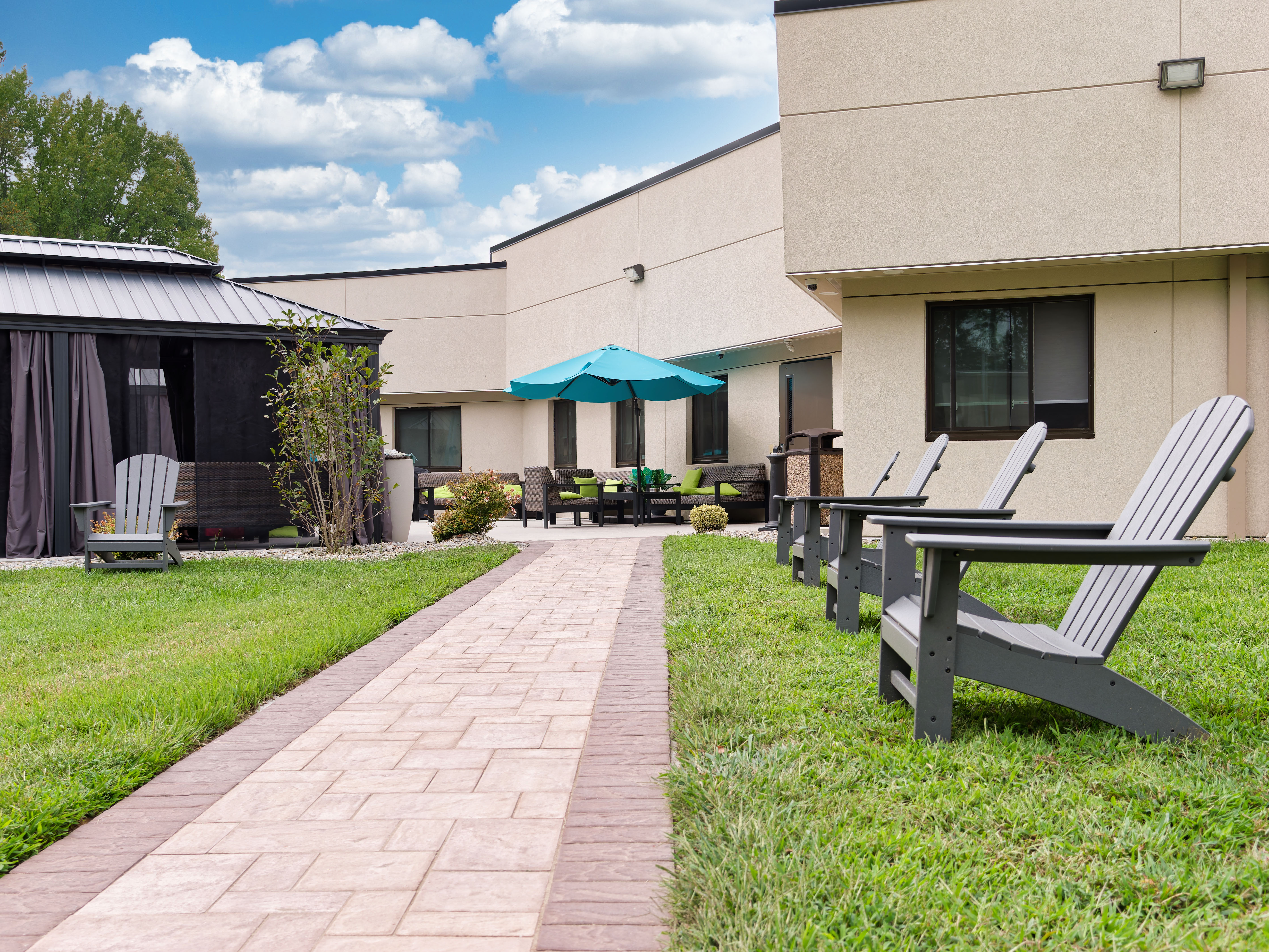 Courtyard with chairs, gazebo, and patio walkway.