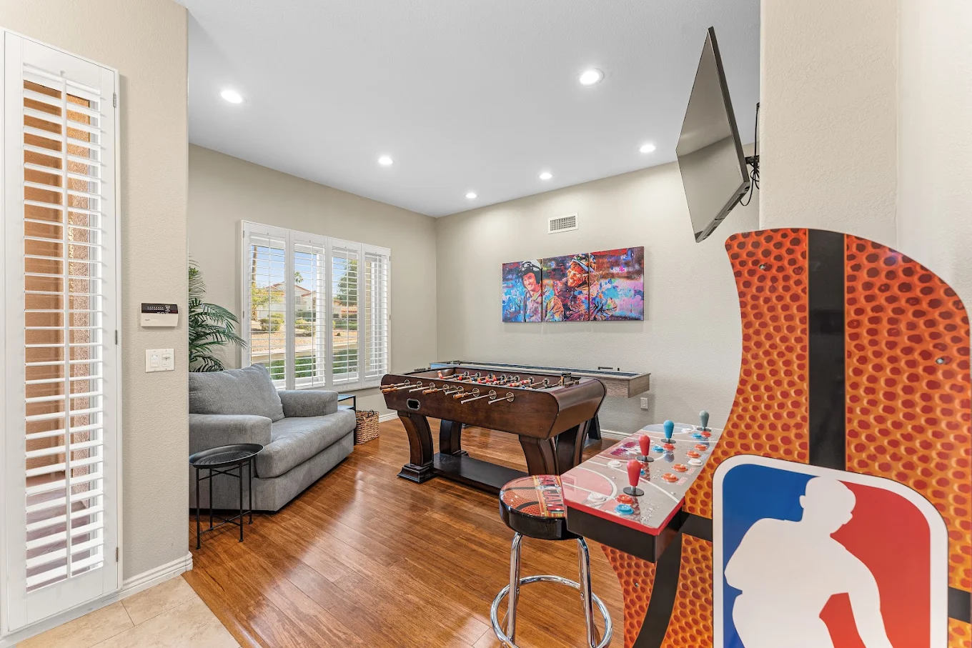 Recreation room with foosball table, arcade game, sofa, and television.
