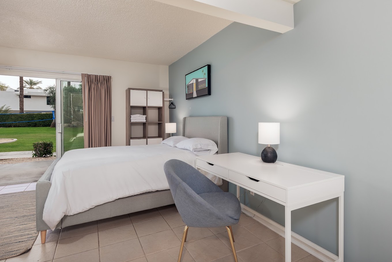 Sunlit bedroom with a bed, desk, and patio access