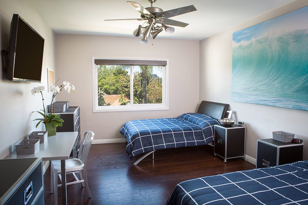 Shared bedroom with two beds and large ocean wave artwork