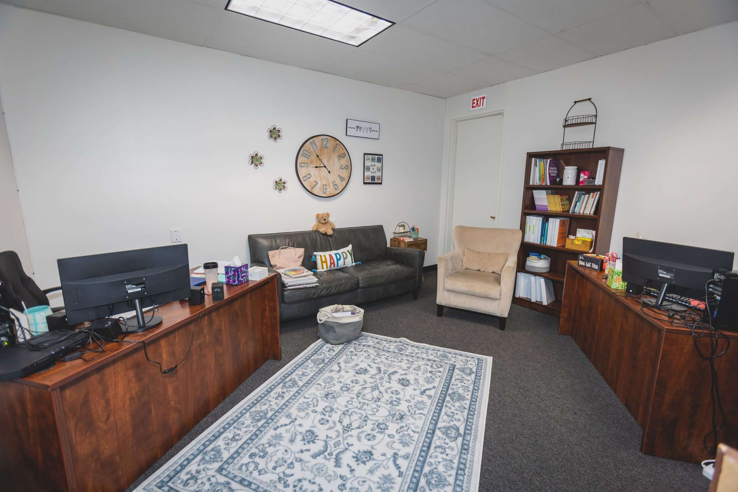 Small office with two desks, sofa, bookshelves, and cozy decor