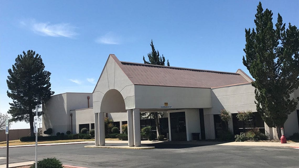 Hospital front entrance with tall peaked roof and driveway