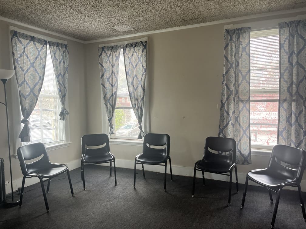 Chairs in a semi-circle facing windows with patterned curtains