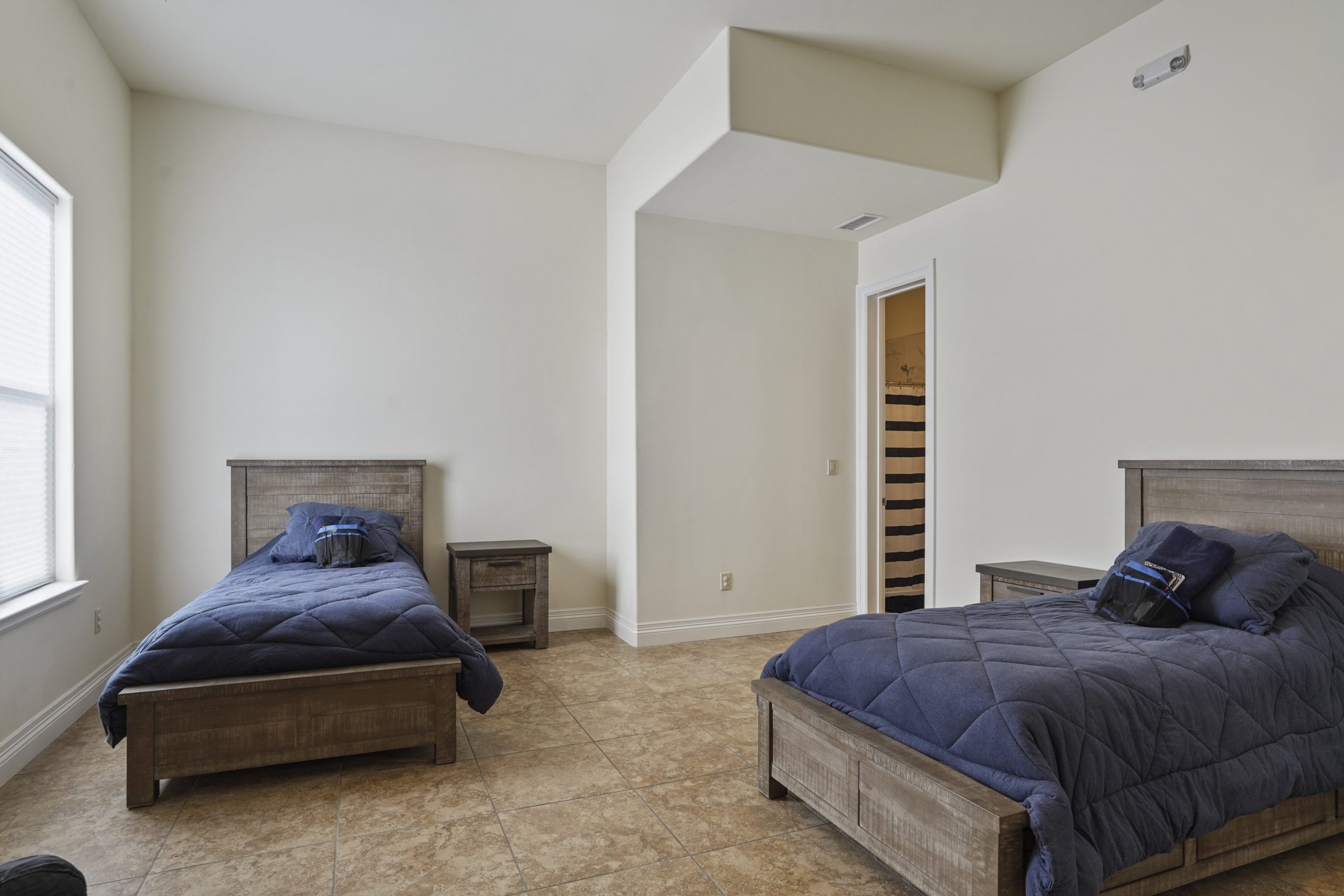 Shared bedroom with two twin beds and tiled flooring.