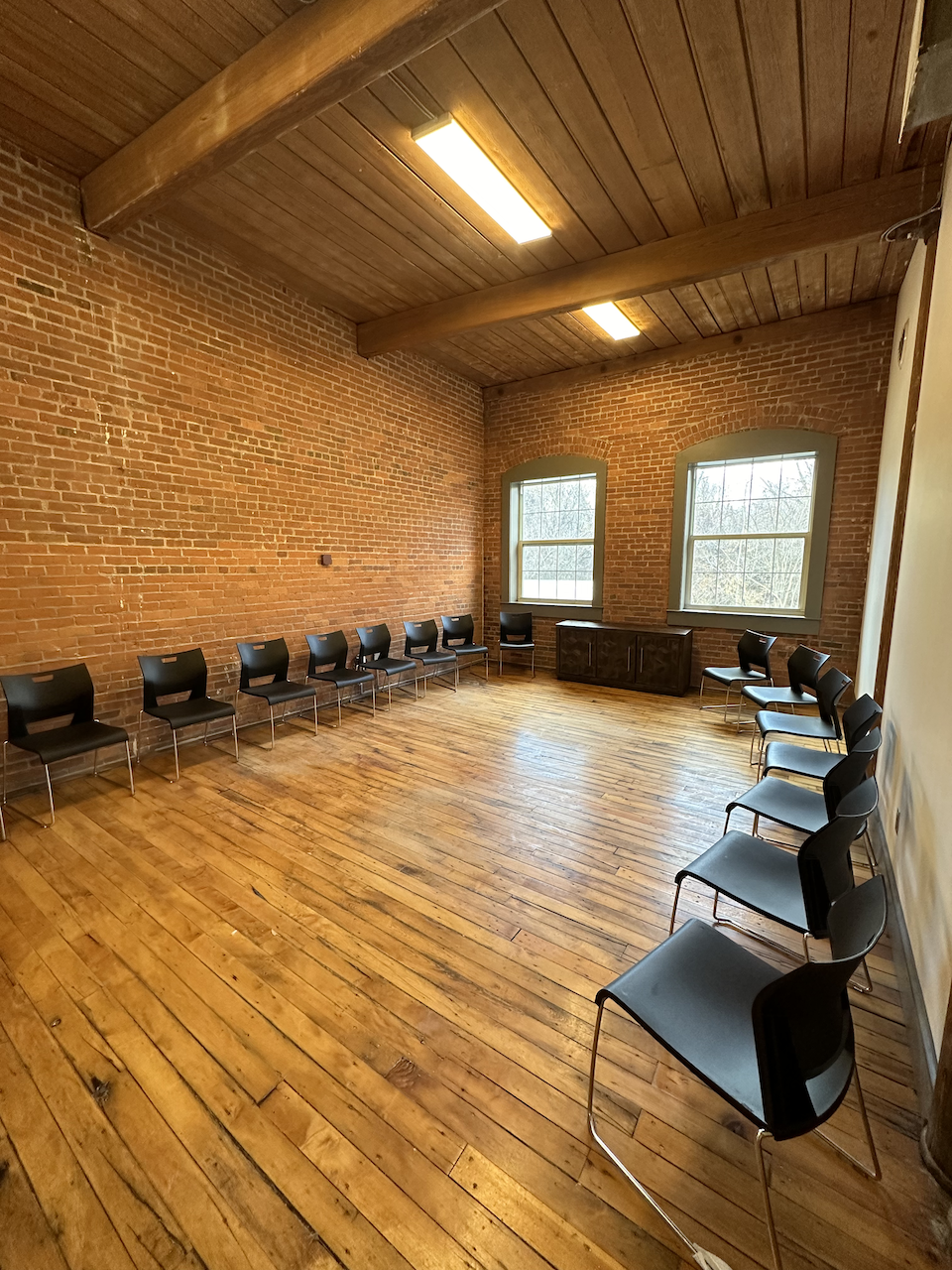 Group meeting space with black chairs along brick walls
