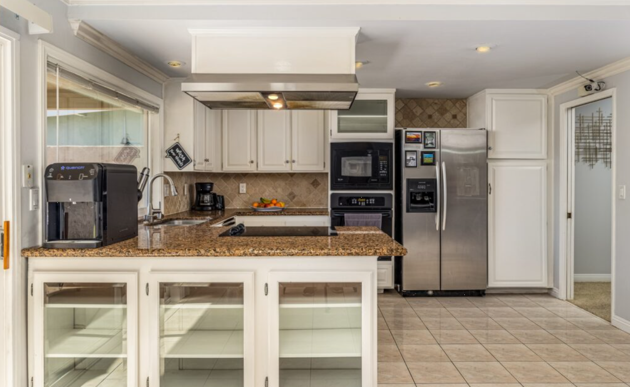 Kitchen with granite counters, white cabinets, and appliances