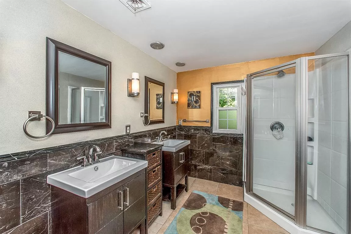 Bathroom with stylish tiles, two sinks, and a walk-in shower.