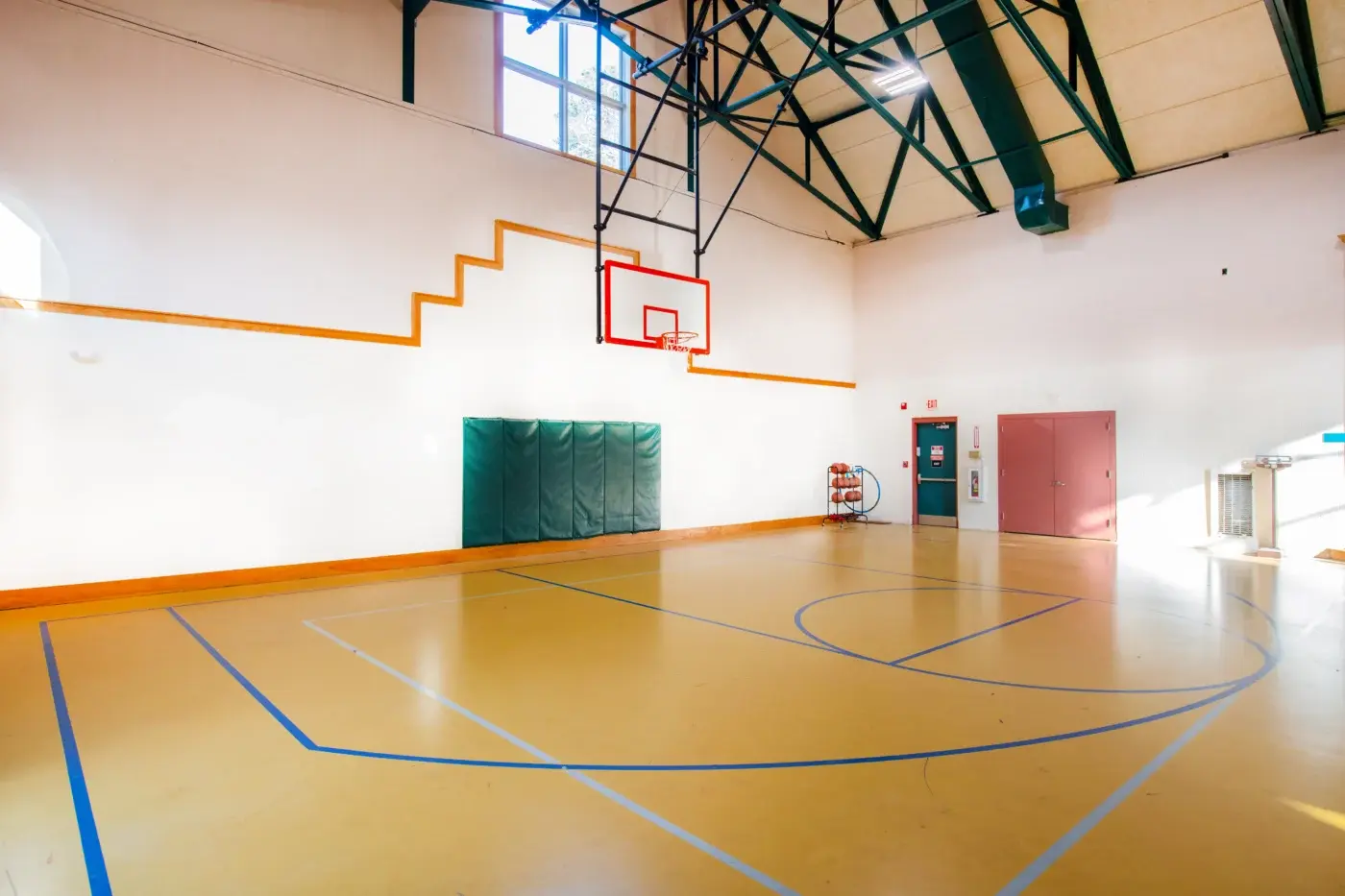 Indoor basketball court with hoop and padded wall